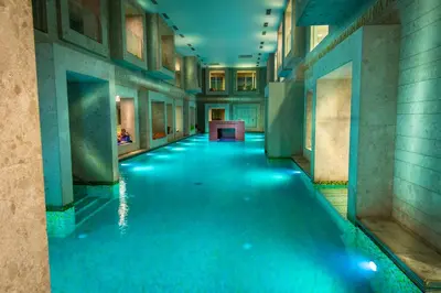 a long hallway with blue water in a building at Rimske Terme Resort - Hotel Sofijin dvor in Rimske Toplice