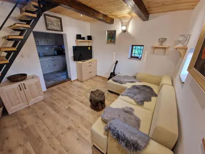 a living room with a couch and a staircase at Vineyard cottage Vinska grajska kašča in Mirna
