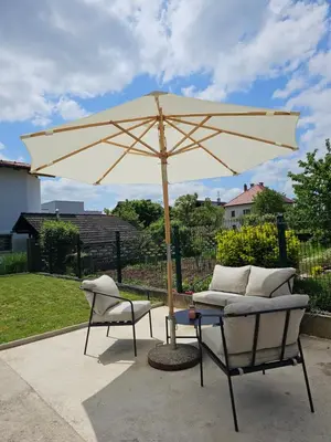 a tan umbrella and two chairs and a table at Apartma FIREFLY2 in Ljubljana