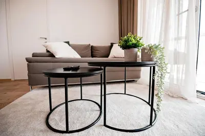 two black tables in a living room with a couch at Sodoben apartma v centru Ljubljane in Ljubljana