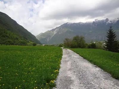a gravel road in a field with mountains in the background at Apartment MT Čezsoča in Bovec