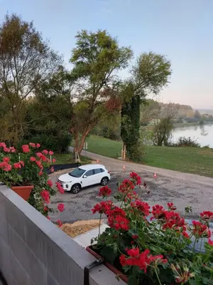 a white car parked in a parking lot with red flowers at Apartma Ob jezeru in Gradišče v Slovenskih Goricah