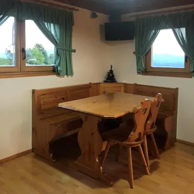 a wooden table and chairs in a room with windows at Vineyard Cottage Janko & Metka in Otočec
