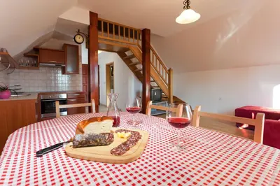 a table with a plate of food and two glasses of wine at Vineyard Cottage Lustek in Novo Mesto