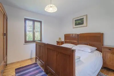 a bedroom with a wooden bed and a window at Vineyard Cottage Vrbek in Roginska Gorca