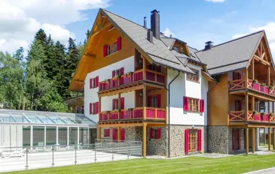a building with red and white balconies next to a house at Awesome Apartment In Pohorje With Wifi in Pohorje