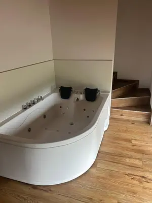 a white bath tub in a room with wooden floors at Borl Apartment in Gradišča