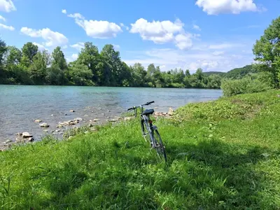 a bike parked in the grass next to a river at LAND FOR YOUR TENT NEXT TO A RIVER WITH A GARDEN SHACK ROOM you get two bicycles for amazing views and two water floats for a nice river run USE THE LOCATION NOT THE ADDRESS TO GET HERE bathroom is a bit different so check YouTube video RiverRunDusko in Ljubljana