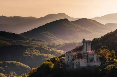 a castle on a hill with mountains in the background at Hostel POINT Nova Gorica, Self Check-In with code access in Nova Gorica