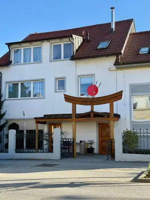 a white building with a large wooden sign on it at Apartma z dvema spalnicama in balkonom in Maribor