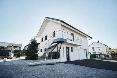 a white house with a staircase in a driveway at Green Alpine Nest in Komenda