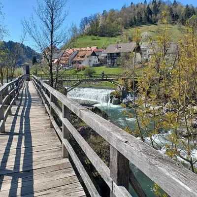 a wooden bridge over a river with a waterfall at Apartma Saint Thomas in Selca