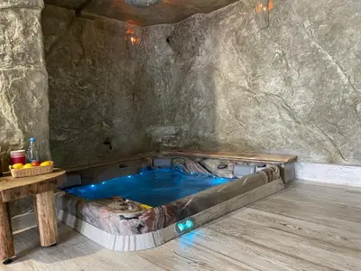 a hot tub in a cave with a wooden table at Zerko Holiday Apartment Janko with JACUZZI and SAUNA in Mirna