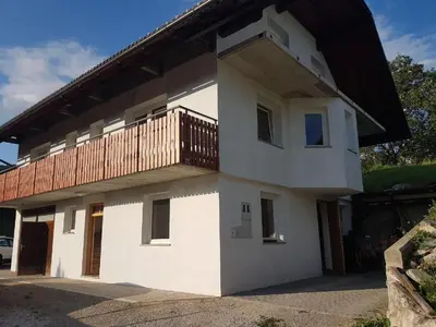 a white house with a balcony on top of it at Apartma Rebeka in Zgornje Gorje
