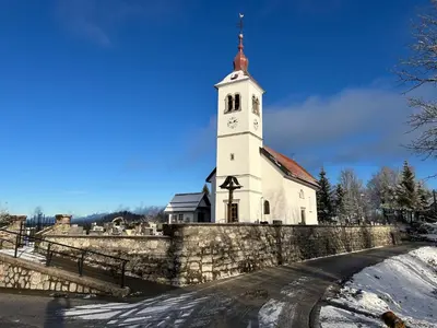 a church with a tower with a clock on it at Hiša p'r Kobalu- in Idrija