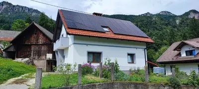 a white house with solar panels on its roof at Apartma Mlinca 1 in Mojstrana