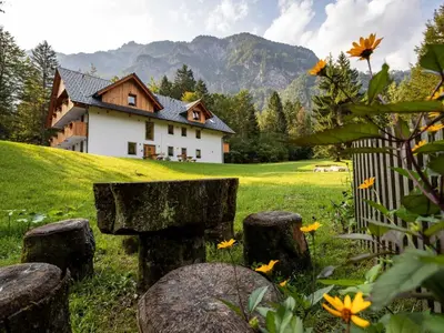 a house on a hill with a fence and flowers at The Woodland Nook Apartments Bohinj - One Bedroom Apartment with Balcony in Bohinj