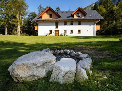a house with a stone arch in front of a house at The Woodland Nook Apartments Bohinj - Classic Two Bedroom Apartment with Balcony in Bohinj