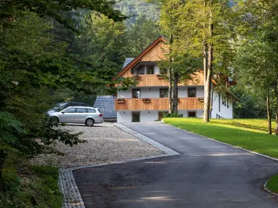 a house with a car parked on the side of a road at The Woodland Nook Apartments Bohinj - Comfort Two Bedroom Apartment with Balcony in Bohinj