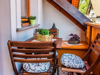 a porch with two chairs and a wooden table and a table and chairs at Riverside Pines Luce Apartments with Balcony - Studio Apartment with Balcony in Luče