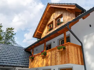 a wooden house with two windows and potted plants at The Woodland Nook Apartments Bohinj - Standard Two Bedroom Apartment with Balcony in Bohinj