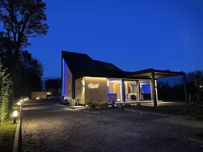 a building with a sign on the side of it at night at Elegant Warm Bliss Hideaway Escape Lodge - Holiday Home with Hot-Tub in Šenčur