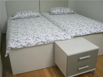 a bed with a dresser and a white bedsheet at House Dolenja Trebuša in Dolenja Trebuša