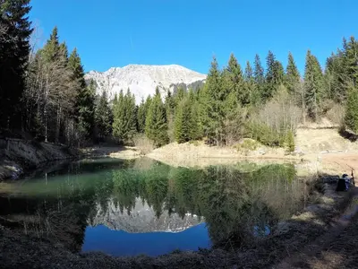a reflection of a mountain in a lake with trees at Karami Mountainhouse in Tržič