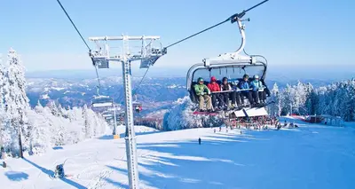 a group of people sitting on a ski lift at Pohorje Village Wellbeing Resort - Forest Hotel Videc in Pohorje
