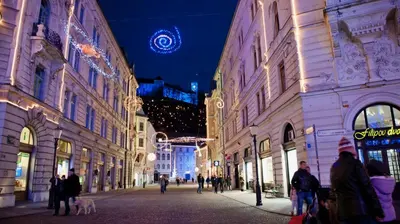 a group of people walking down a street at night at i Design Apartment in Ljubljana