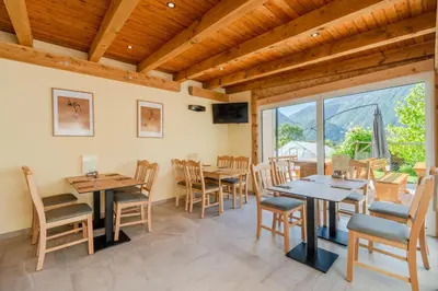 a dining room with tables and chairs and a large window at Penzion Hosnar, apartma Time Out in Bovec