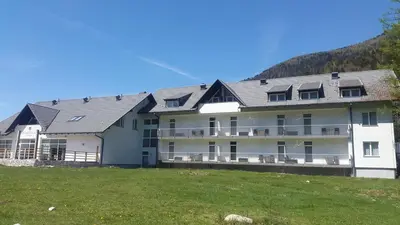 a large white building with a hill in the background at Klass 302 in Kranjska Gora