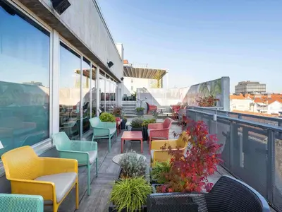 a patio with colorful chairs and tables on a balcony at ibis Styles Ljubljana Centre in Ljubljana