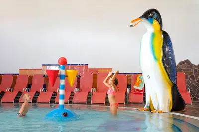 a little girl standing in the water next to a penguin at Terme Zreče – Vile Terme Zreče in Zreče
