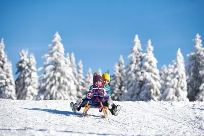 two children sitting on a sled in the snow at Terme Zreče – Vile Terme Zreče in Zreče