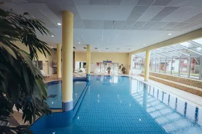 a large swimming pool with blue tiles in a building at Pohorje Village Wellbeing Resort - Wellness & Spa Hotel Bolfenk in Pohorje