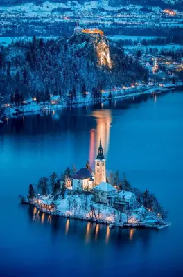 an island in the middle of a lake at night at Lake Bled Apartment Marjetka in Bled