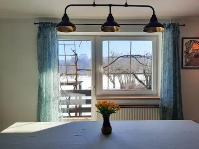 a vase of flowers sitting on a table in front of a window at Deerwood Holiday Cozy Retreat 2br Apartment with Stunning Castle Views in Bled