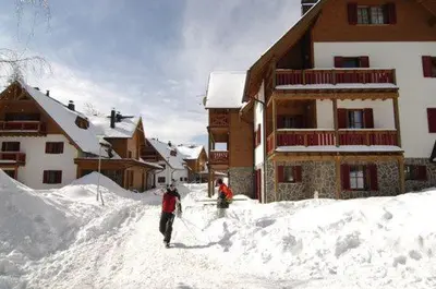 two people standing in the snow in front of a lodge at Antela, 142 m2 appartment for 12 person in Mariborsko Pohorje in Pohorje