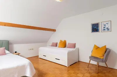 a bedroom with two beds and a chair at HoMEMADE in Ljubljana
