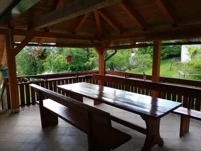 a wooden bench on a porch with a table at Apartmaji Pika in Cerklje na Gorenjskem