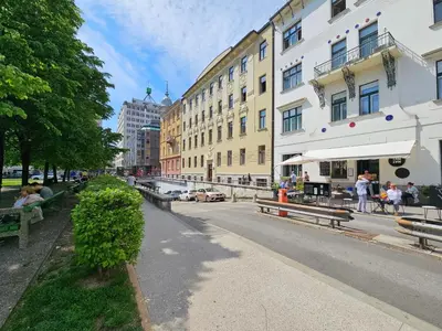 people sitting on benches on a city street with buildings at Studio Apartment Gea Tour As Ljubljana in Ljubljana