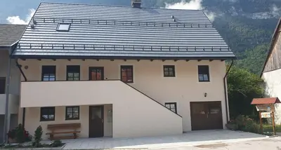 a white house with a black roof at APARTMAJI VITEZ apartma 2 in Bovec