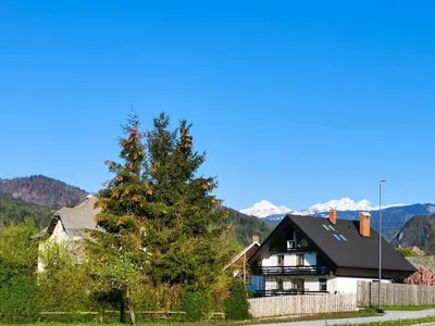 a house with a tree and mountains in the background at Deerwood-Sky Attic with Bled Castle View-NO KITCHEN in Bled