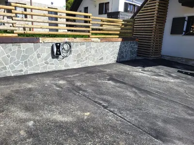 a driveway with a stone wall and a fence at Apartments Nune in Zreče