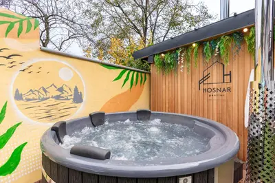 a hot tub in front of a wall with a sign at Penzion Hosnar, apartma Lev in Bovec