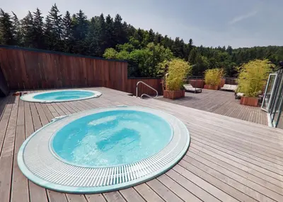 a large swimming pool on a deck with a wooden deck at Spa Suite Dobrna - Terme Dobrna in Dobrna