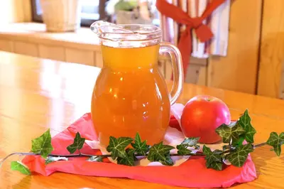 a pitcher of apple juice and an apple on a table at Farm Stay Trlej in Begunje na Gorenjskem