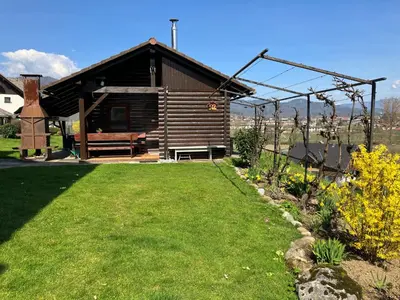 a wooden cabin with a bench in a yard at Cottage Barbara with Sauna in Škofja Loka