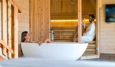 a man and a woman sitting in a bath tub at Brunarica Macesen Smogavc in Zreče